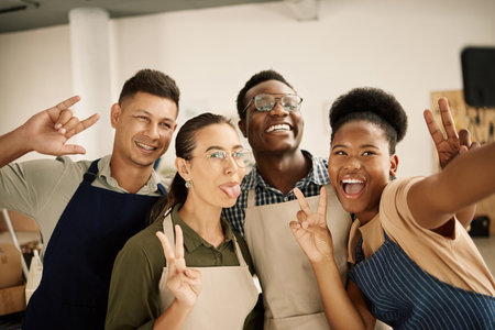 Group of excited designers taking a selfie. Cheerful colleagues taking selfie on a cellphone. Diverse fashion designers making gestures. Businesspeople making funny facial expressions taking a selfieの写真素材