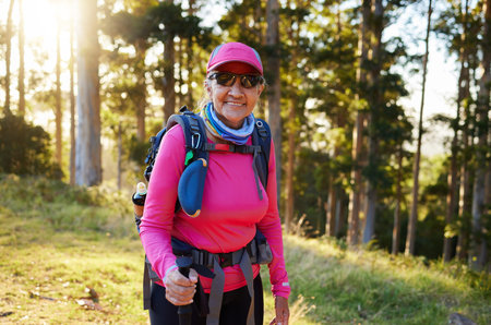 Hiking, nature and summer with a senior woman in the forest or woods, walking for health and exercise. Trees, fitness and hike with an elderly female pensioner taking a walk in the mountain in summerの写真素材
