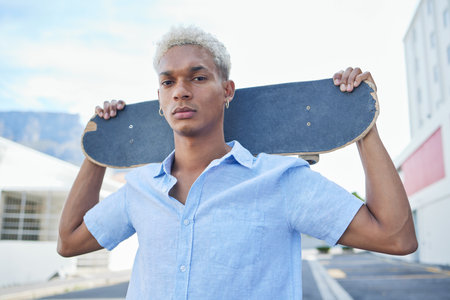 Black man, serious with a skateboard and city, urban background and trendy, hipster fashion in portrait. Young African American hobbies, skater and gen z youth outdoors at skatepark during summer.の写真素材
