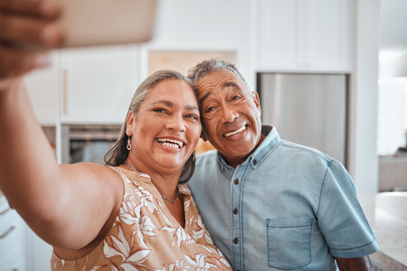 Selfie, senior couple and happy in kitchen at home being romantic, fun and smile together for anniversary. Retirement, elderly man and woman being loving, bonding or relax indoors for love or romanceの写真素材