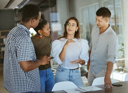 Group of businesspeople standing and talking together in an office. Hispanic businesswoman doing a...