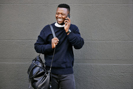 African american male on a phone call with his mobile device outside a building during the day while...