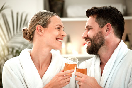 Spa couple, wine glass toast and celebration of love, relax and wellness luxury hotel on vacation together. Smile man, happy woman and champagne drink cheers at body massage salon to celebrate dateの写真素材