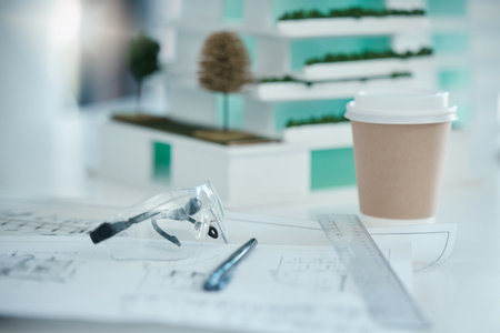 Architecture, planning and design on desk with drawing tools, safety glasses and coffee. Blueprint, vision and idea for architect, engineer or construction worker in building or construction industryの写真素材
