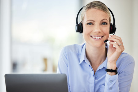 Portrait of young caucasian female call centre agent talking on headset while working on computer in...