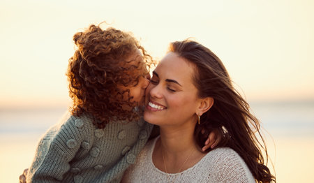 Loving mixed race mother at the beach with adorable little daughter. Mom and child enjoying beach day during summer vacation. Single mother enjoying quality time with her daughter against copyspaceの写真素材