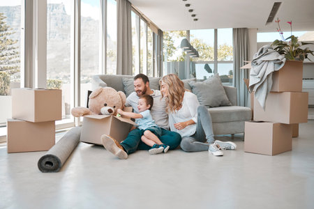 Happy family in a new home. Parents sitting on the floor with child. Young caucasian mother and father with son packing boxes. Smiling little boy in a big, open house with mom and dadの写真素材