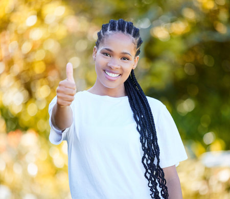 Do your best today. a beautiful young woman showing thumbs up while standing outdoors.の写真素材