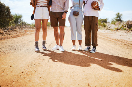 Shoes, shadow and friends on a sand road in the desert for summer holiday or vacation while walking together in nature. Travel, legs and adventure with a man and woman group standing on a footpathの写真素材