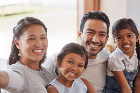 Just a happy family. Cropped portrait of an affectionate young family of four taking selfies on the sofa at home.の写真素材