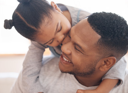 Closeup adorable little girl smiling and hugging her single father inside at home. Cute mixed race child enjoying weekend free time with single parent. Hispanic man bonding and holding his daughterの写真素材