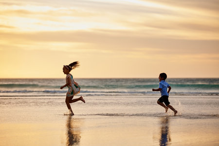 Were dreaming. a little boy and girl playing chase at the beach.の写真素材