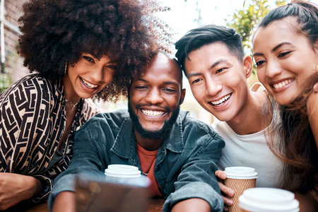 Diverse group of friends browsing and taking selfies on a cellphone while drinking coffee at a cafe together. Cheerful young students socialising at a restaurant. Two couples enjoying a double dateの写真素材