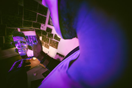 Unknown masked man with mental disorder alone at night feeling paranoid. Hidden man mentally ill, depressed and wearing a mask in his bedroom. Artist having a crisis looking in a cracked mirrorの写真素材