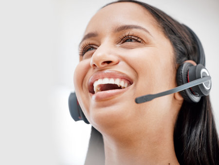 One young hispanic happy and cheerful female call center agent wearing a headset and working in customer service at work. Face of a hispanic woman answering calls working at a call centerの写真素材