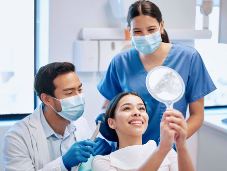 A smile she can be proud of. a young woman checking her results in the dentists office.の写真素材