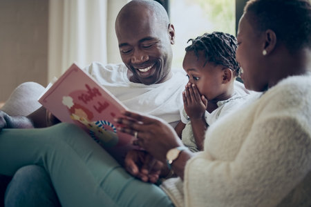 I didnt see that coming. a young family reading a book together at home.の写真素材