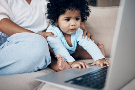 Watching her favourite show. an unrecognizable woman using a laptop with her daughter on the sofa at home.の写真素材