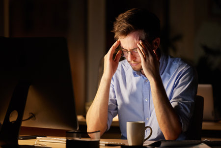 I didnt sign up for this kind of stress. a young businessman looking stressed out while working on a computer in an office at night.の写真素材