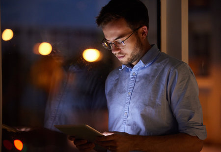 The smart entrepreneur. a young businessman using a digital tablet in an office at night.の写真素材