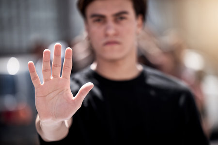 Someone has to stop the madness. a young man with his hand raised during a protest.の写真素材