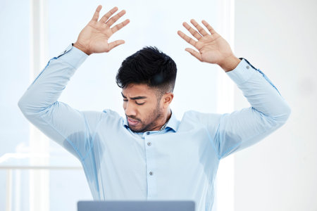 All sweaty and stressed. a young businessman with sweat stained through the underarms of his shirt.