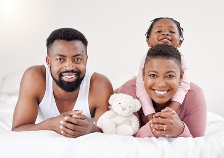 Warm, cozy and rested. a young family bonding in bed together.の写真素材
