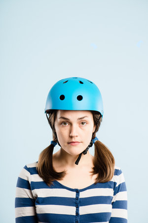 Do I have to wear this. an attractive young woman standing alone in the studio and posing while wearing a helmet.の写真素材