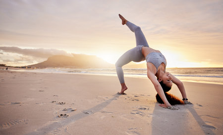 Your body is capable of great things. a young woman practicing yoga on the beach.