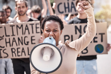 The world cannot stay complacent. a young woman shouting through a megaphone at a protest.の写真素材