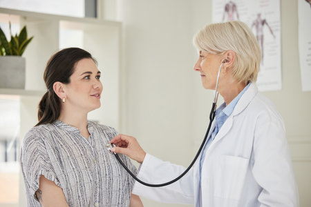 Dedicated to keeping you healthy. a mature doctor listening to a patients heartbeat using a stethoscope.の写真素材