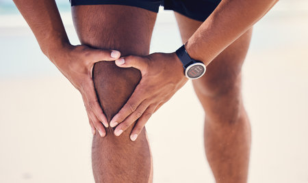 Oh, my knee. a man experiencing discomfort in his knee while out for a workout.の写真素材