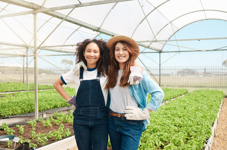 Gardening is an investment that brings a significant impact in life. Portrait of two young women working on a farm.の写真素材