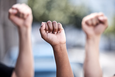 Demanding what they deserve. a group of protestors with their hands raised in the air.の写真素材
