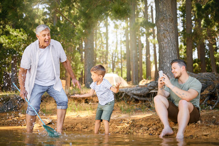 They will each have these great moments to cherish. a little boy having fun with his father and grandfather at a lake in a forest.の写真素材