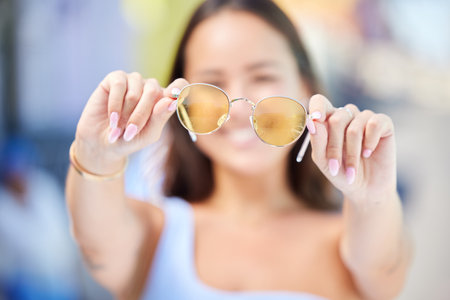 Summer, fashion and sunglasses in hands of woman for style and beauty. Sunshine, holiday and Asian woman with stylish accessories in the city to enjoy vacation, travel and adventure on a sunny dayの写真素材