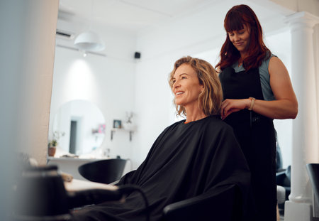 Beauty, hairdresser and happy customer at a salon for grooming, fancy and beautiful makeover. Smile, wellness and professional stylist working on an elegant senior client or mature woman in Canadaの写真素材