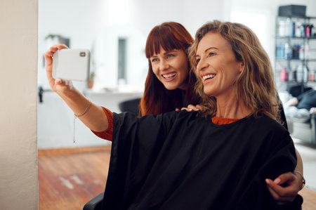Selfie, women and designer hairdresser spa hair care day at salon studio. Beauty, senior customer and young hair stylist take photograph on mobile phone at successful small grooming businessの写真素材