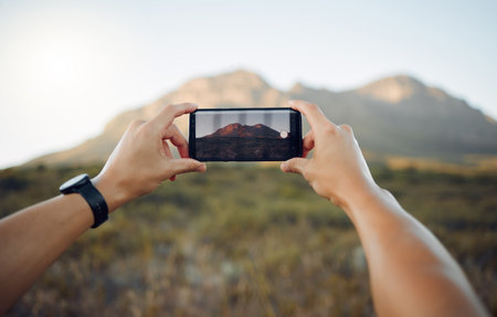 Hands, phone and mountain picture in nature for adventure, travel and countryside in the outdoors. Hand of traveler taking a photo of the natural environment with mobile smartphone in South Africaの写真素材