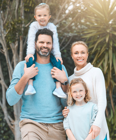.a couple and their two daughters posing together in a park.の写真素材