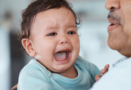 Why arent they listening. an unrecognizable man holding his crying grandchild at home.の写真素材