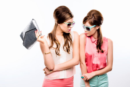 Am I seeing double. Studio shot of two attractive young women dressed up in 60s wear against a white background.の写真素材