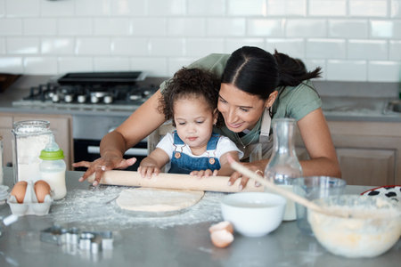 Rolling with mom today. a young mom baking with her toddler at home.の写真素材