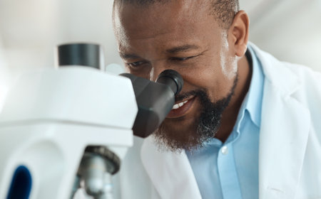 Im looking right at the problem. a handsome mature scientist using a microscope to analyse a sample in the laboratory.の写真素材