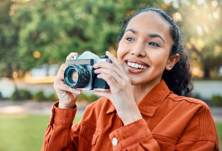 Creative juices flowing. a young woman holding her camera while standing outside.の写真素材