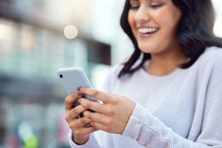 Were never working alone with a good network. a young businesswoman using a smartphone against an urban background.の写真素材