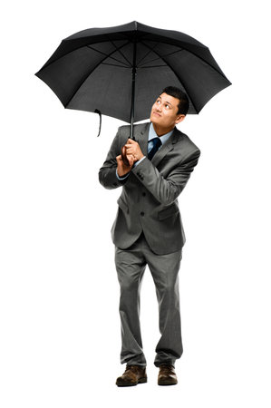 Getting the necessary coverage. a young businessman holding his umbrella against a studio background.の写真素材
