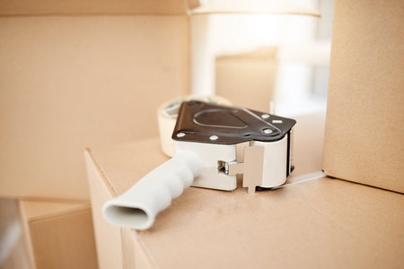 Sealed tight for transit. Closeup shot of a tape dispenser on a cardboard box.の写真素材
