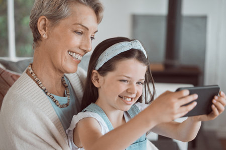 My beautiful granny. a mature woman taking a selfie with her granddaughter at home.の写真素材