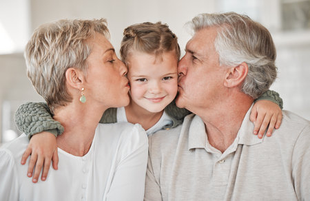 They fill our days with joy. a happy senior couple and their granddaughter relaxing on the sofa at home.の写真素材